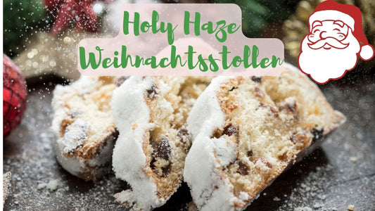 Anschnitt eines Holy Haze Weihnachtsstollens mit Puderzucker, Rosinen und Mandeln auf Holzbrett – festliche Weihnachtsstimmung.